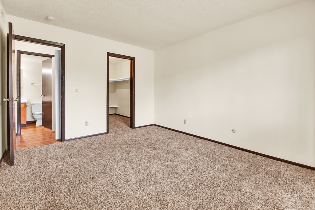 A room with a carpeted floor and two open doors.