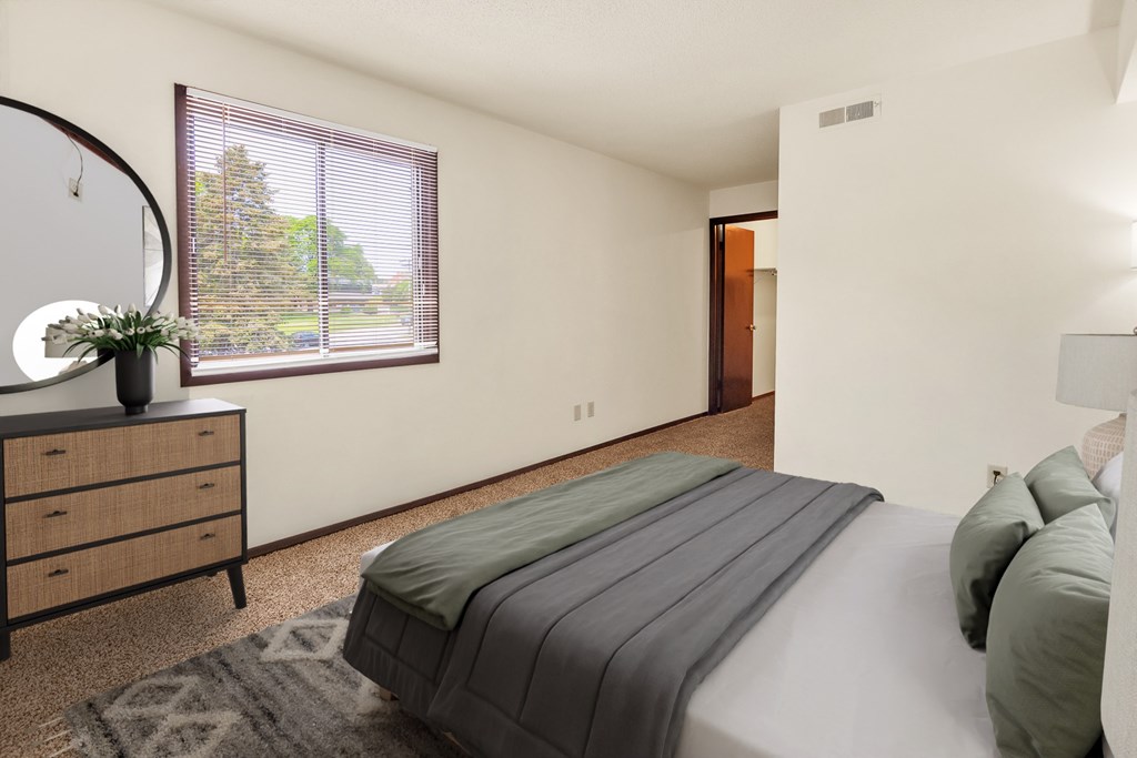 A bedroom with a bed, dresser, and window.