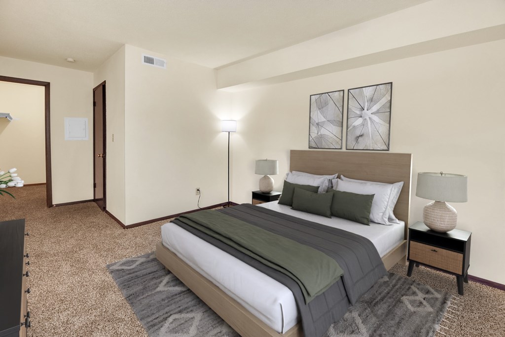 A bedroom with a large bed and a carpeted floor.