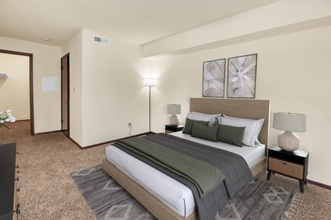 A bedroom with a large bed and a carpeted floor.