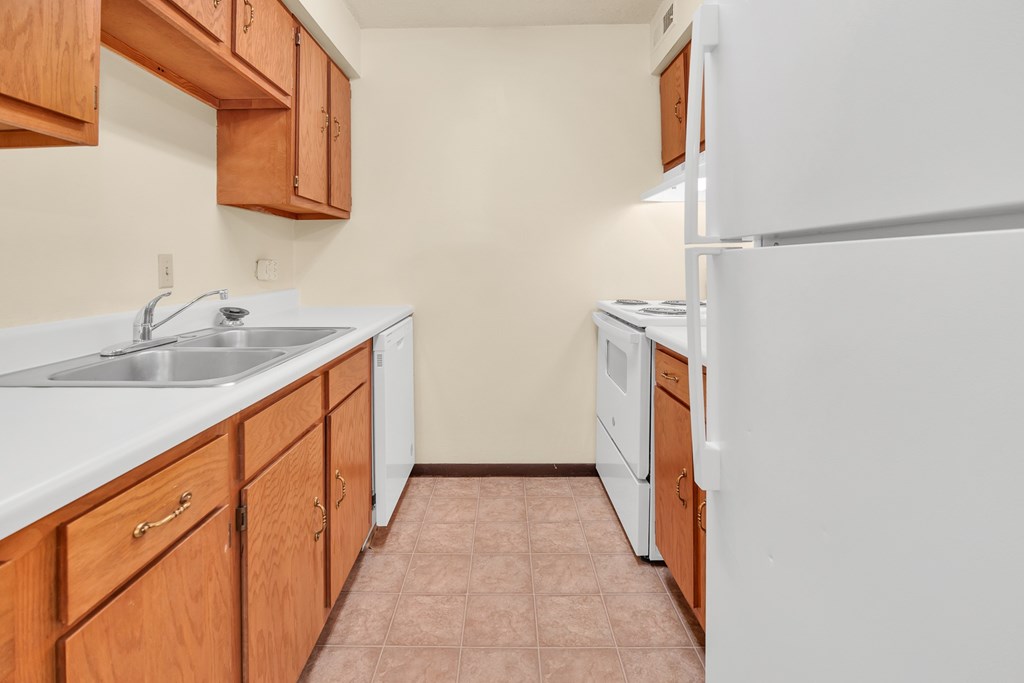 A kitchen with white appliances and wooden cabinets.