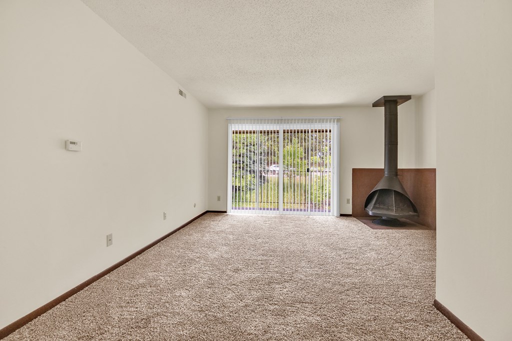 A room with a carpet floor and a fireplace.