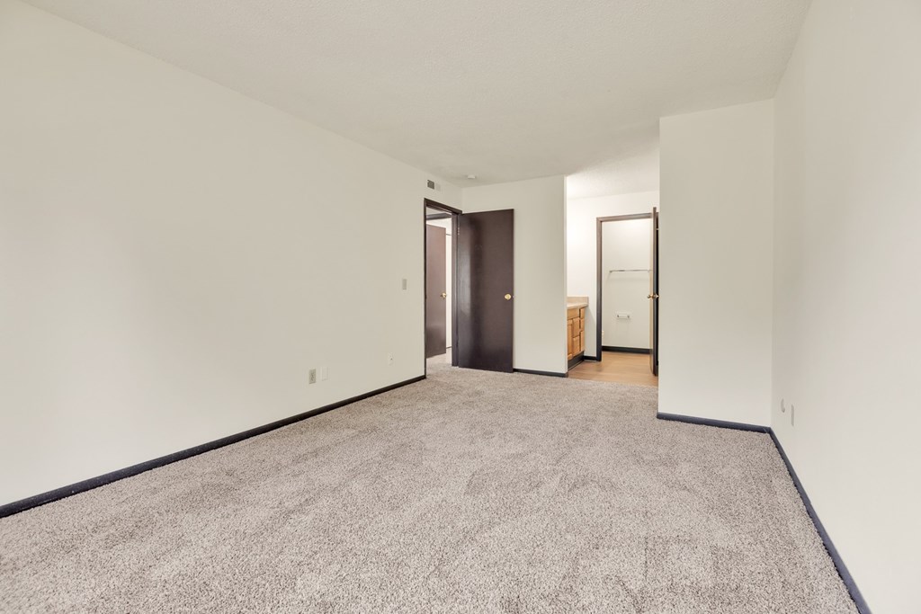 A carpeted hallway with a door on the left and a door on the right.