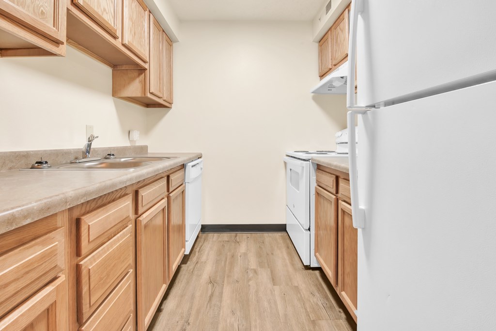 A kitchen with wooden cabinets and a white refrigerator.