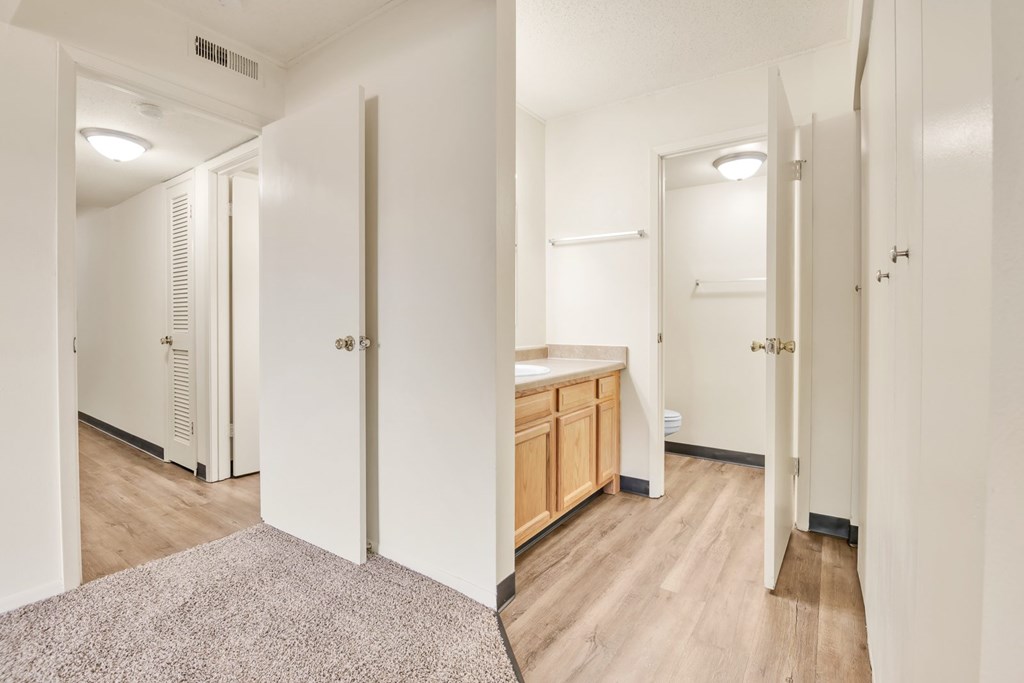 A hallway with a rug on the floor and a door on the left.
