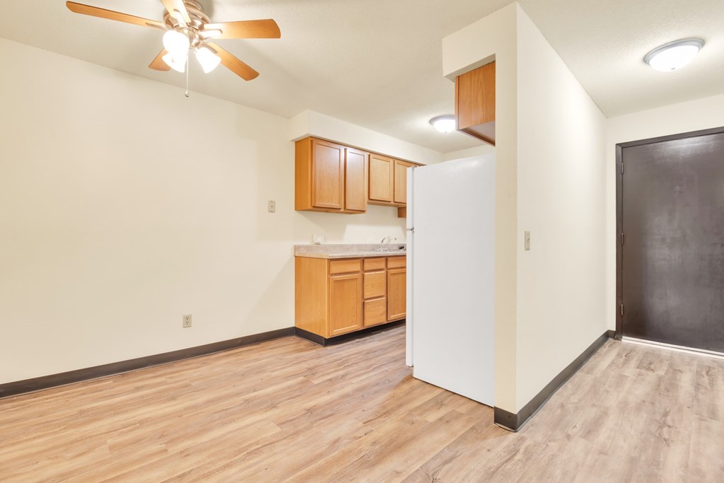 A kitchen with wooden floors and a ceiling fan.