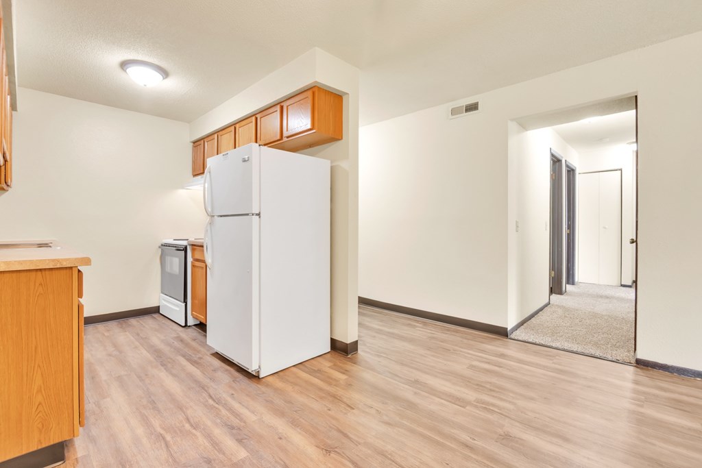 A kitchen with a white refrigerator and wooden cabinets.