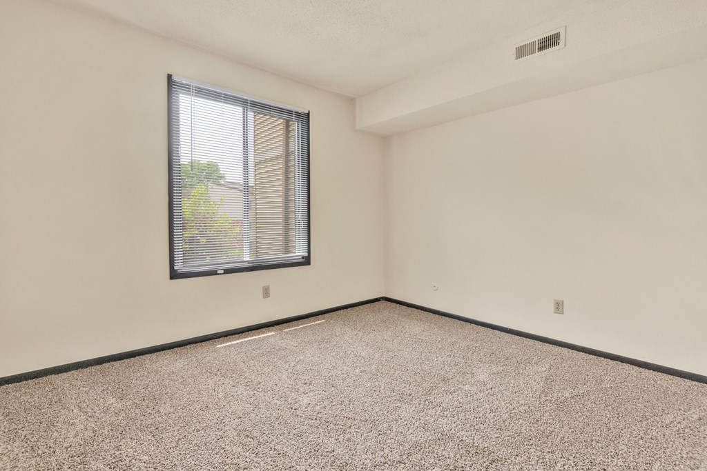 A room with a window and carpeted floor.