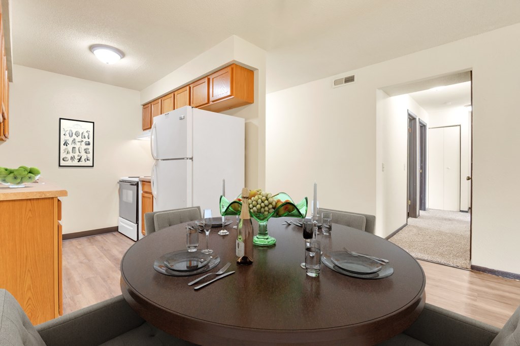 A dining table set with a green vase of flowers and two glasses of water.