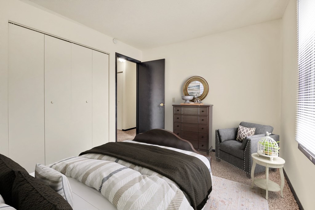 A bedroom with a bed, chair, and wardrobe.