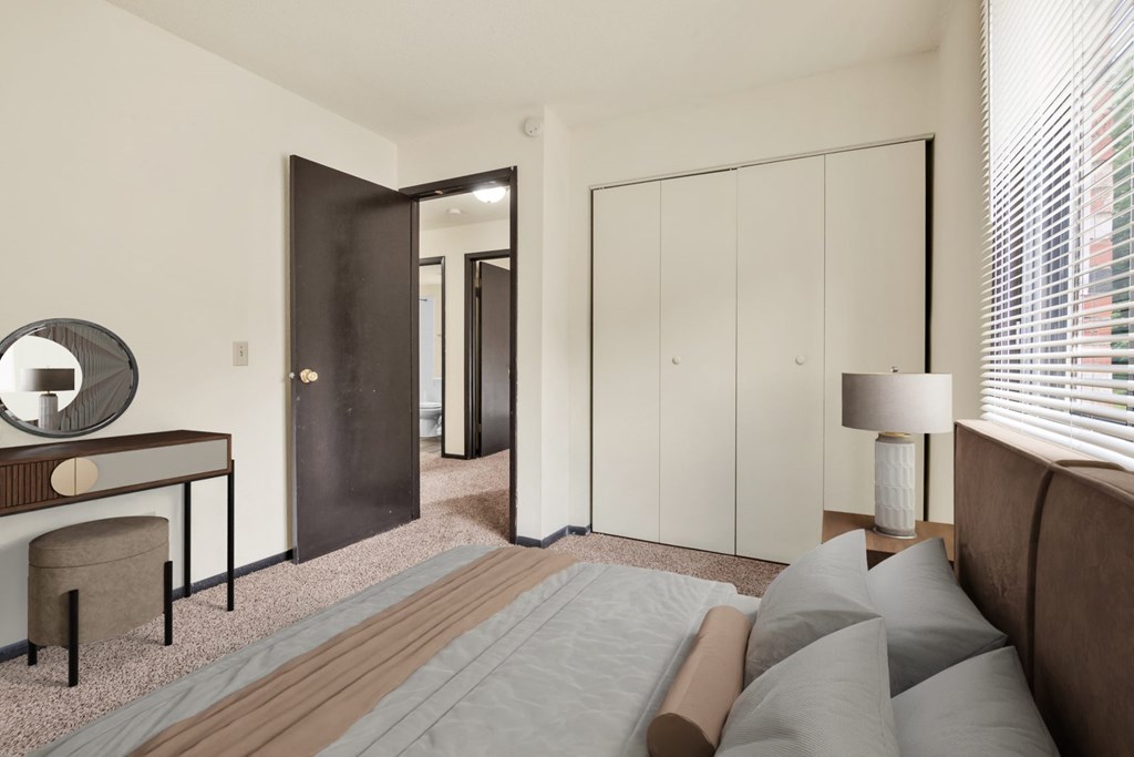 A bedroom with a bed, a desk, and a wardrobe.