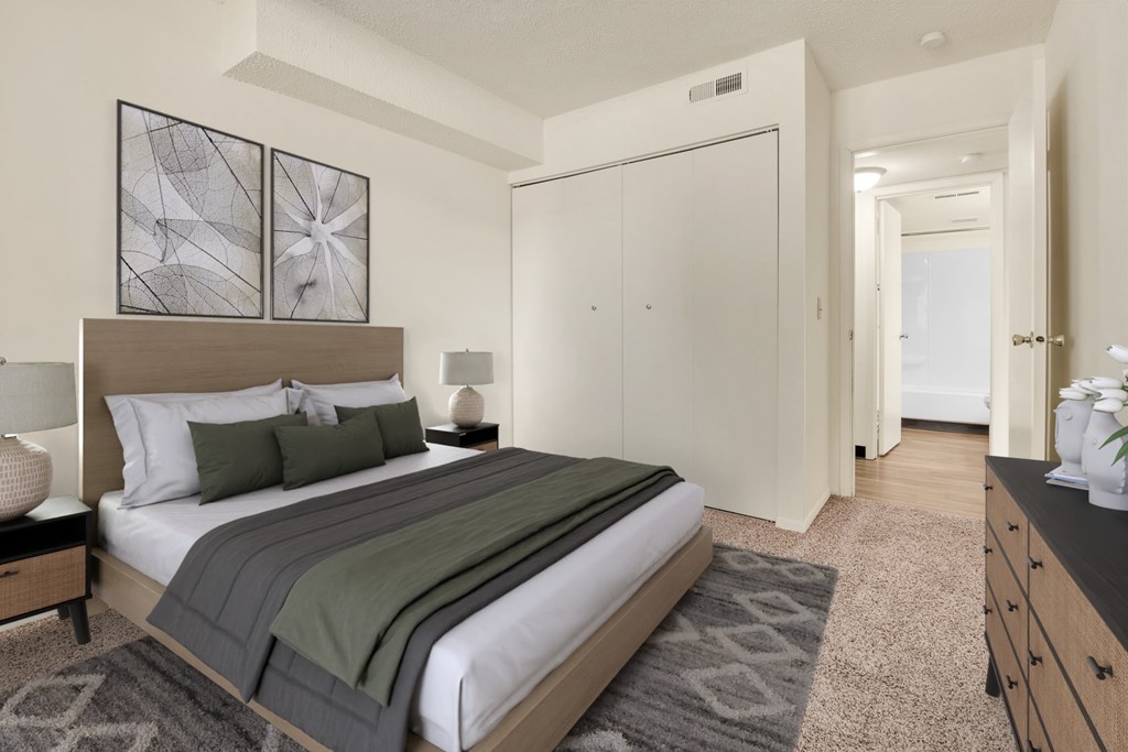 A bedroom with a bed, nightstand, and two framed pictures on the wall.