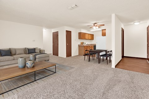 A living room with a grey carpet and a wooden coffee table.