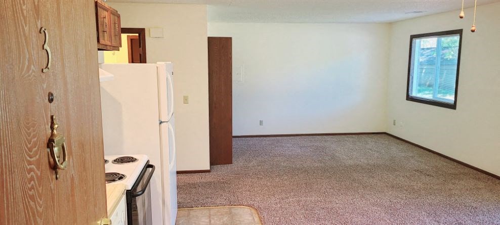 a living room with a refrigerator and a kitchen
