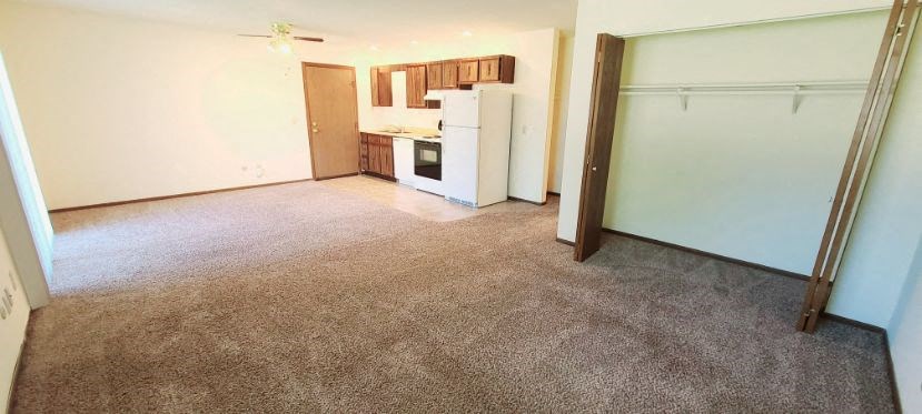 an empty room with a kitchen and a refrigerator