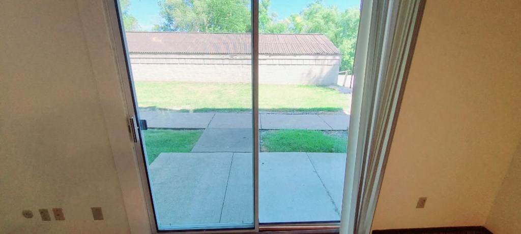 a sliding glass door with a view of a yard and a house