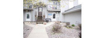 A grey building with a brown door and a sign that says "Office".