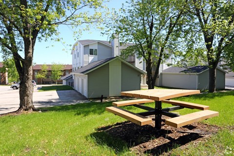 A picnic table sits in the grass in front of a house.