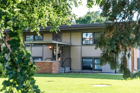 A house with a green lawn and trees in front.