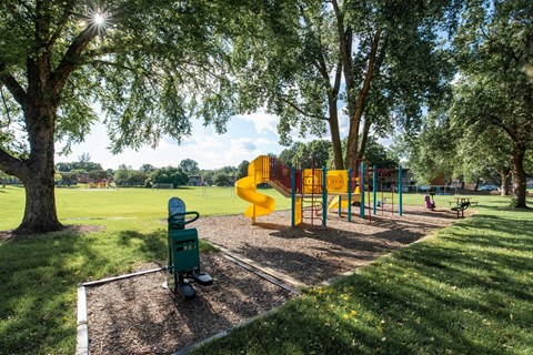 A playground with a yellow slide and a green toy chest.