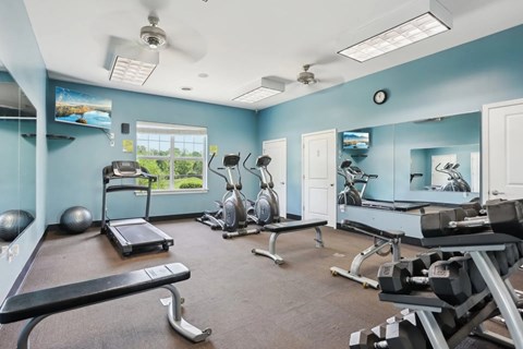 A gym with a variety of equipment including treadmills, weights, and exercise machines.