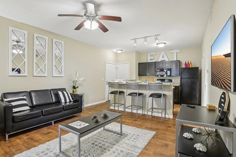 A black leather couch sits in a living room with a glass coffee table in front of it.