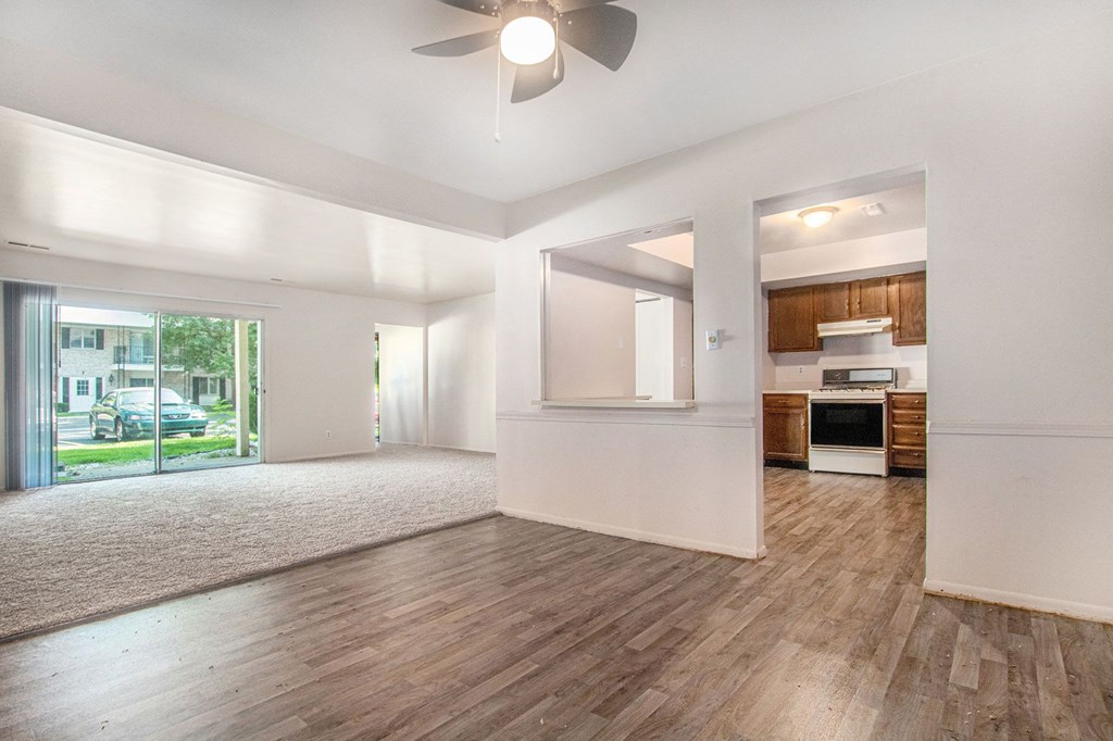 an empty living room with a ceiling fan and a kitchen