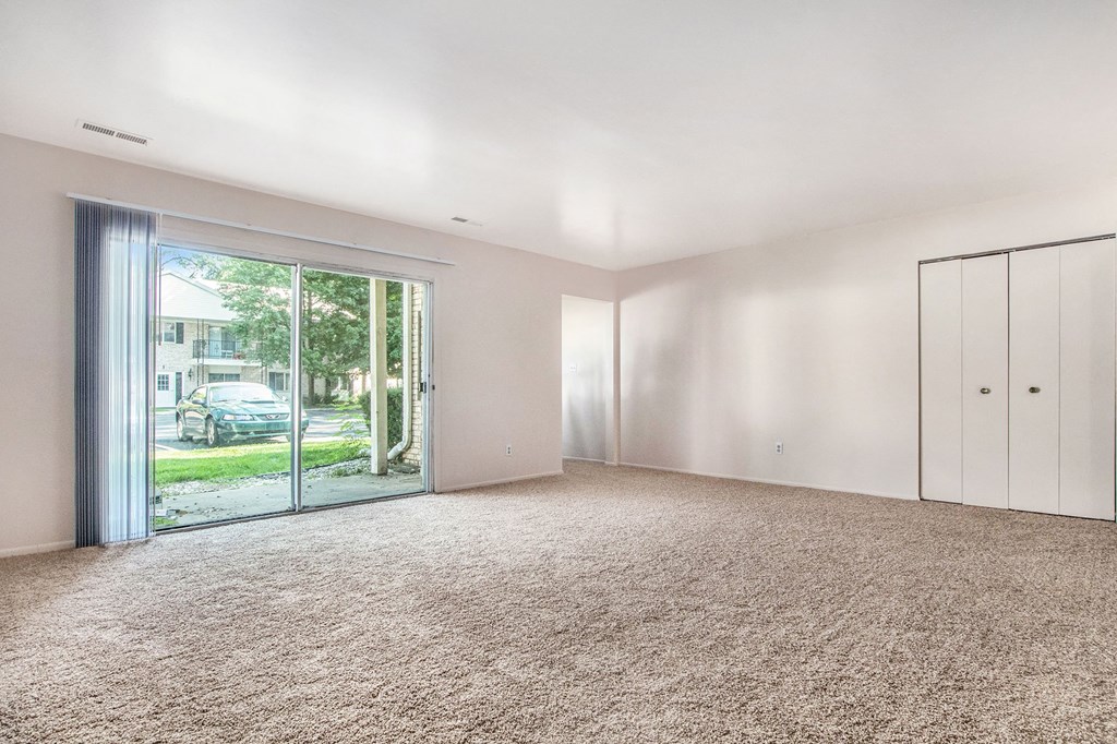 an empty living room with white walls and a sliding glass door