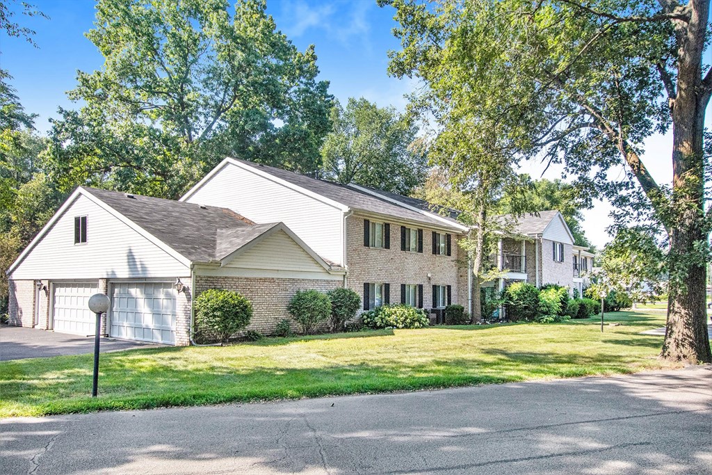 the front of a white house with a yard and trees