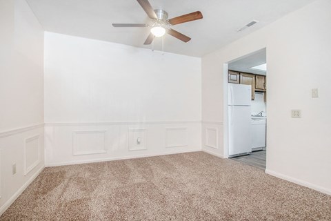A room with a ceiling fan and a refrigerator in the corner.