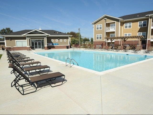 a swimming pool with lounge chairs in front of an apartment building