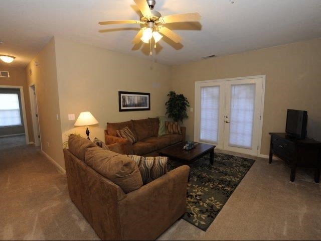 a living room with brown couches and a ceiling fan