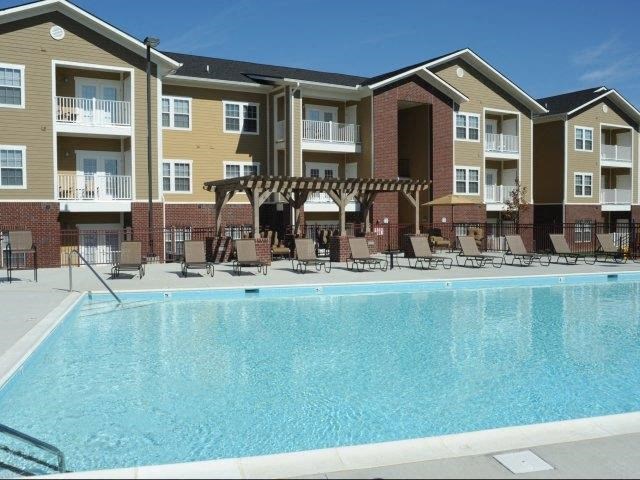 a swimming pool with chairs in front of an apartment building
