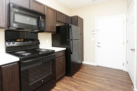 A black stove and refrigerator in a kitchen with wood cabinets.