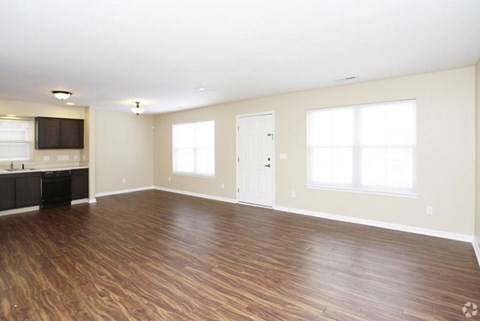 A spacious room with wooden flooring and white walls.
