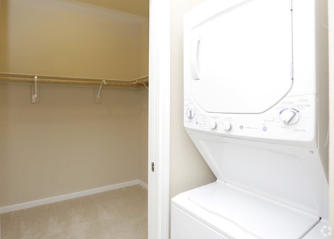 A white dryer is in a room with a tan wall.