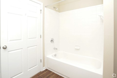A white bathroom with a tub and a door.