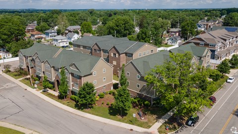 A large building with a green roof is surrounded by trees and other buildings.