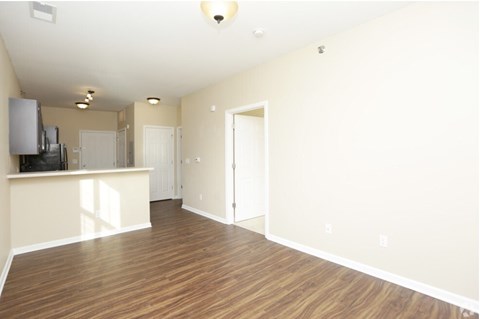A spacious room with wooden flooring and white walls.