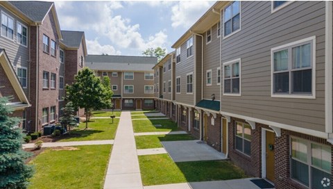 A long, narrow walkway separates two rows of apartment buildings.