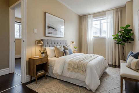 A bedroom with a large bed and a plant on the side table.