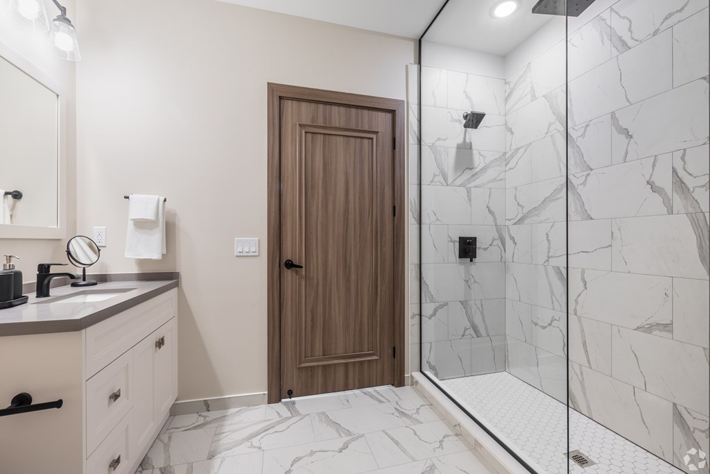 A bathroom with a marble floor and a wooden door.