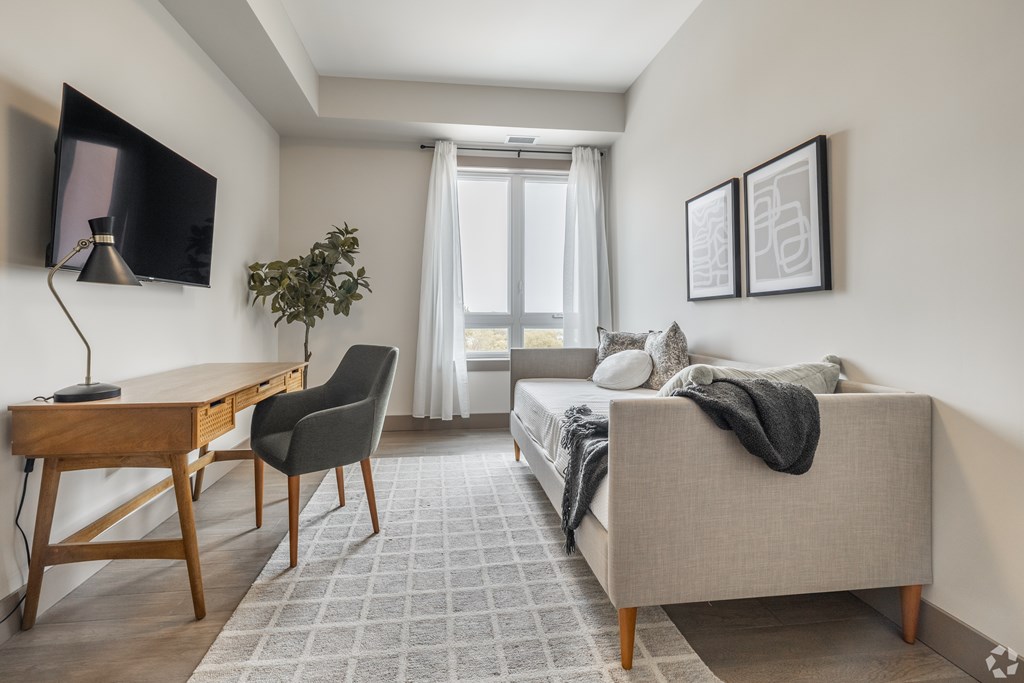 A modern bedroom with a large bed, a desk, and a chair.