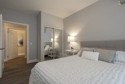 A bedroom with a large bed and a nightstand with a lamp.