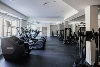 A gym with a row of treadmills and elliptical machines at The Woods at 180 Kanata Avenue, Kanata, Ontario