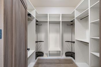 A walk-in closet with white shelving and a wooden floor