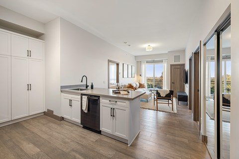A kitchen with white cabinets and a wooden floor.