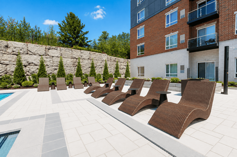 A row of brown lounge chairs are arranged on a patio.