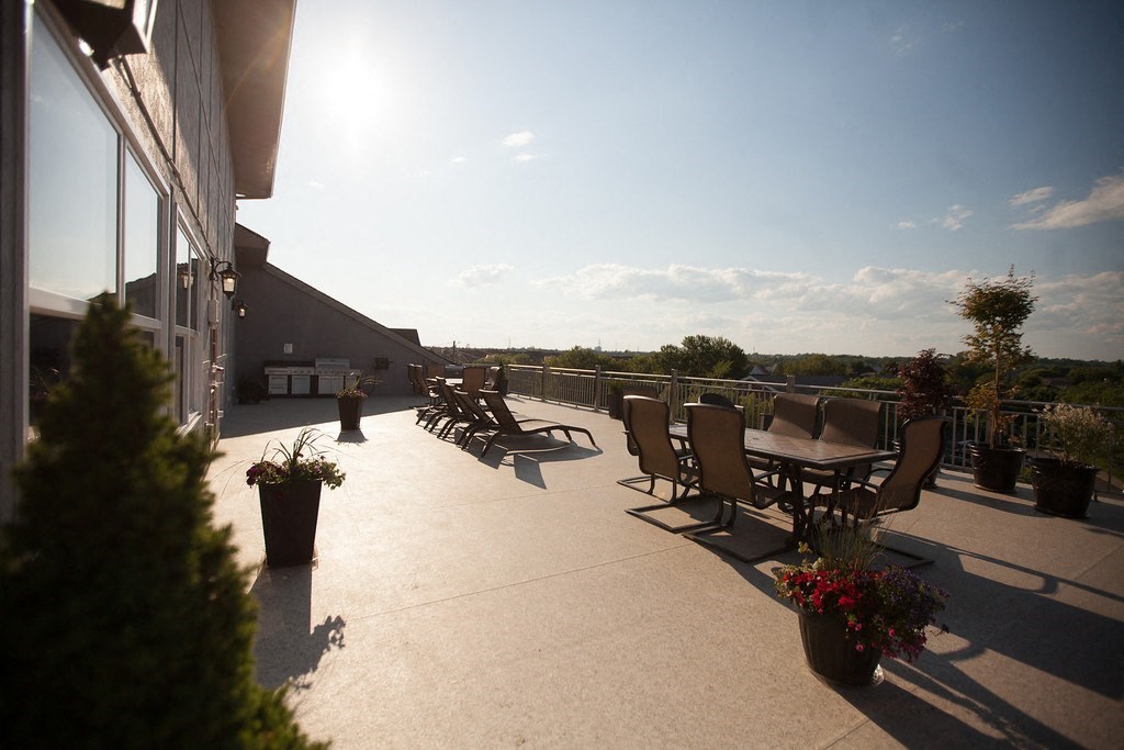 a roof terrace with tables and chairs and a view of the sky