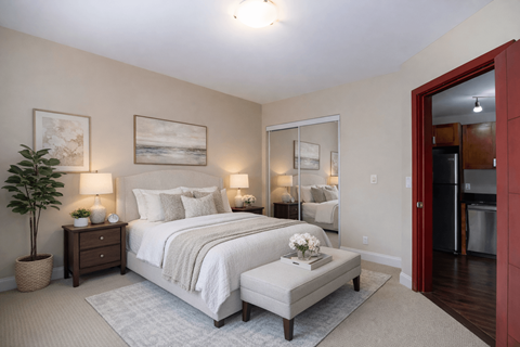 A bedroom with a large bed and a potted plant.